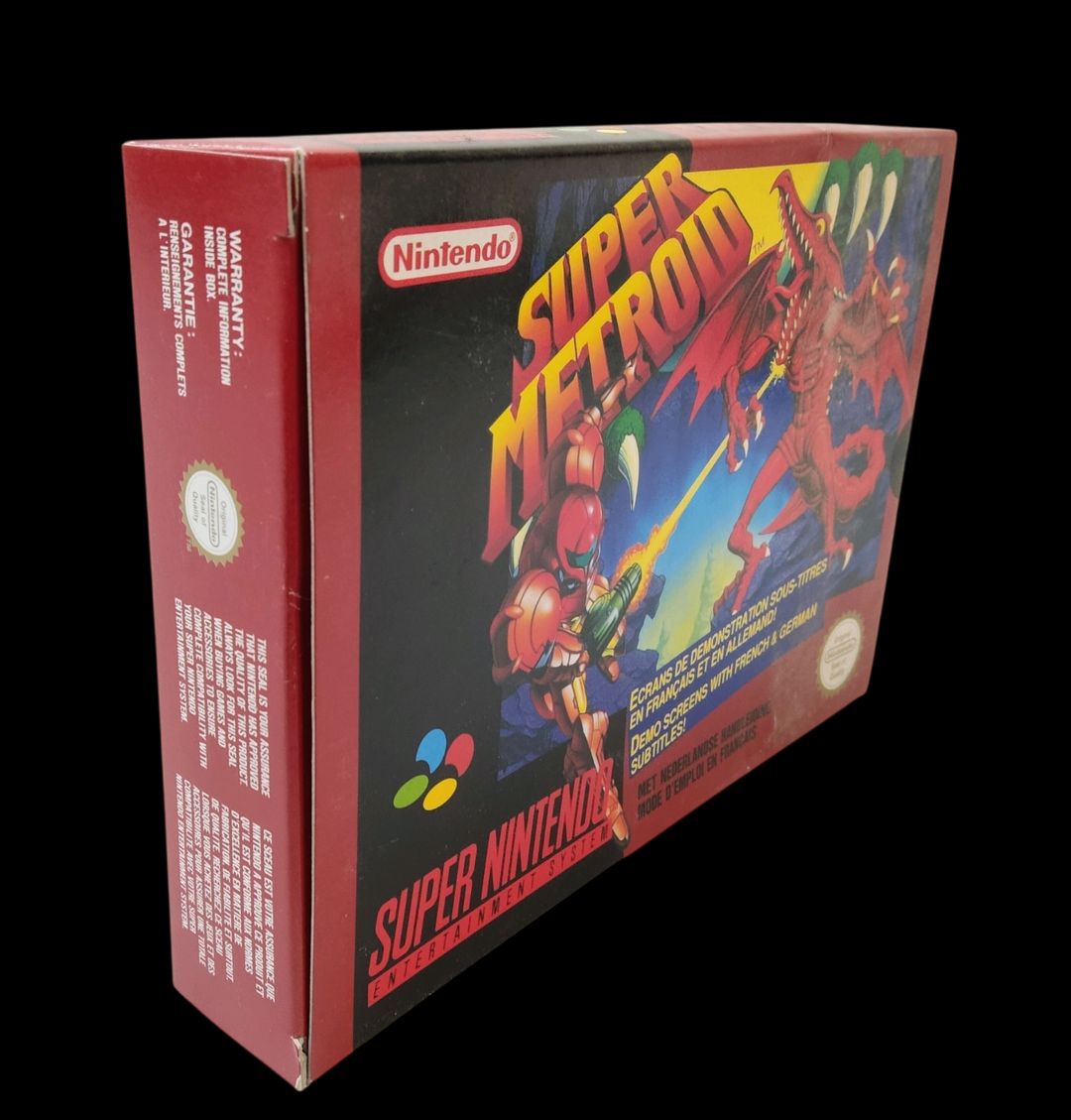 Nintendo – Super Nes – Jeu : Super Metroid. Avec boîte, cale en carton, notice, poster. Version du jeu FAH. Scellage présent sur un côté de la boîte, légères poussières sur la face avant de la boîte.